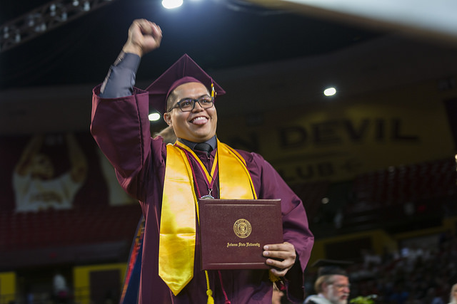 Graduate raising his fist happily and holding his diploma
