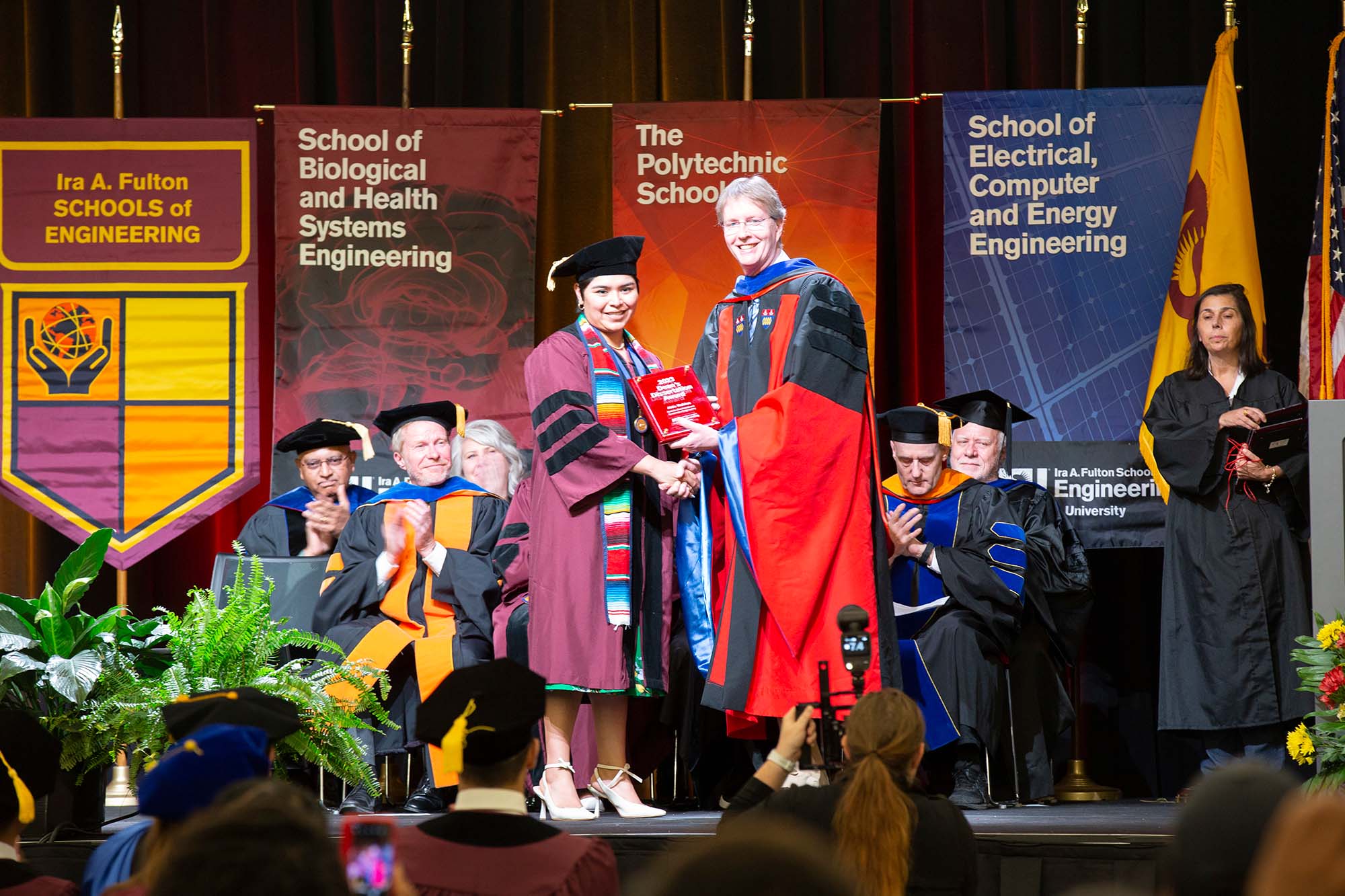 An ASU Engineering PhD graduate shakes hands with Dean Squires as she receives her diploma