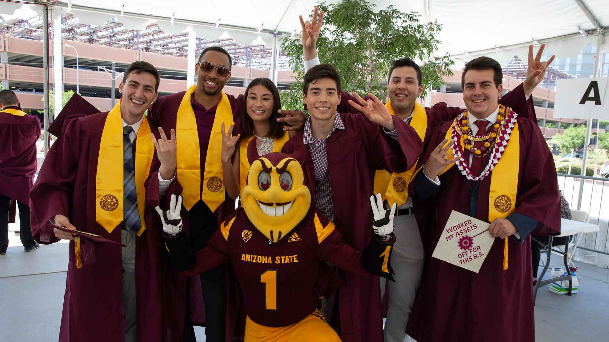 Fulton Schools graduates gather outside Wells Fargo Arena at convocation checkin and pose with Sparky