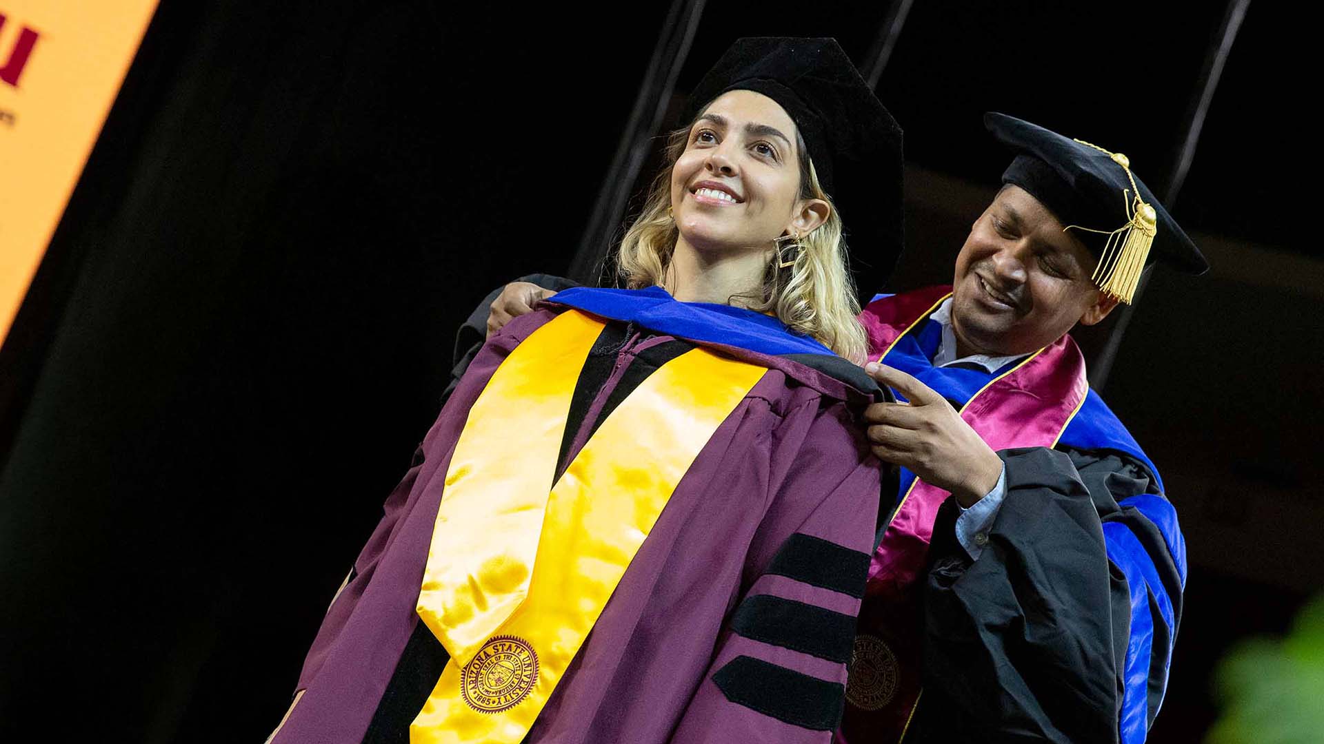 An ASU PhD graduate is hooded by her academic mentor at the Fall 2021 ASU Engineering Convocation ceremony