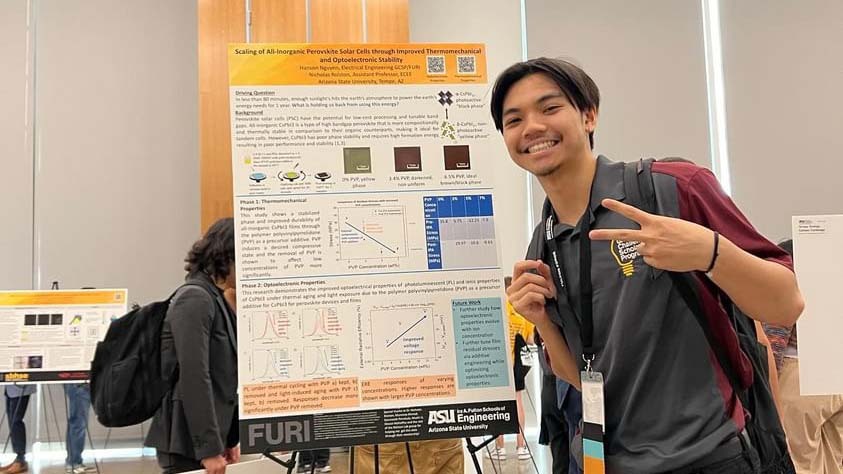 Nguyen Hanson stands smiling and making a peace sign in front of a research poster at an ASU Engineering event.